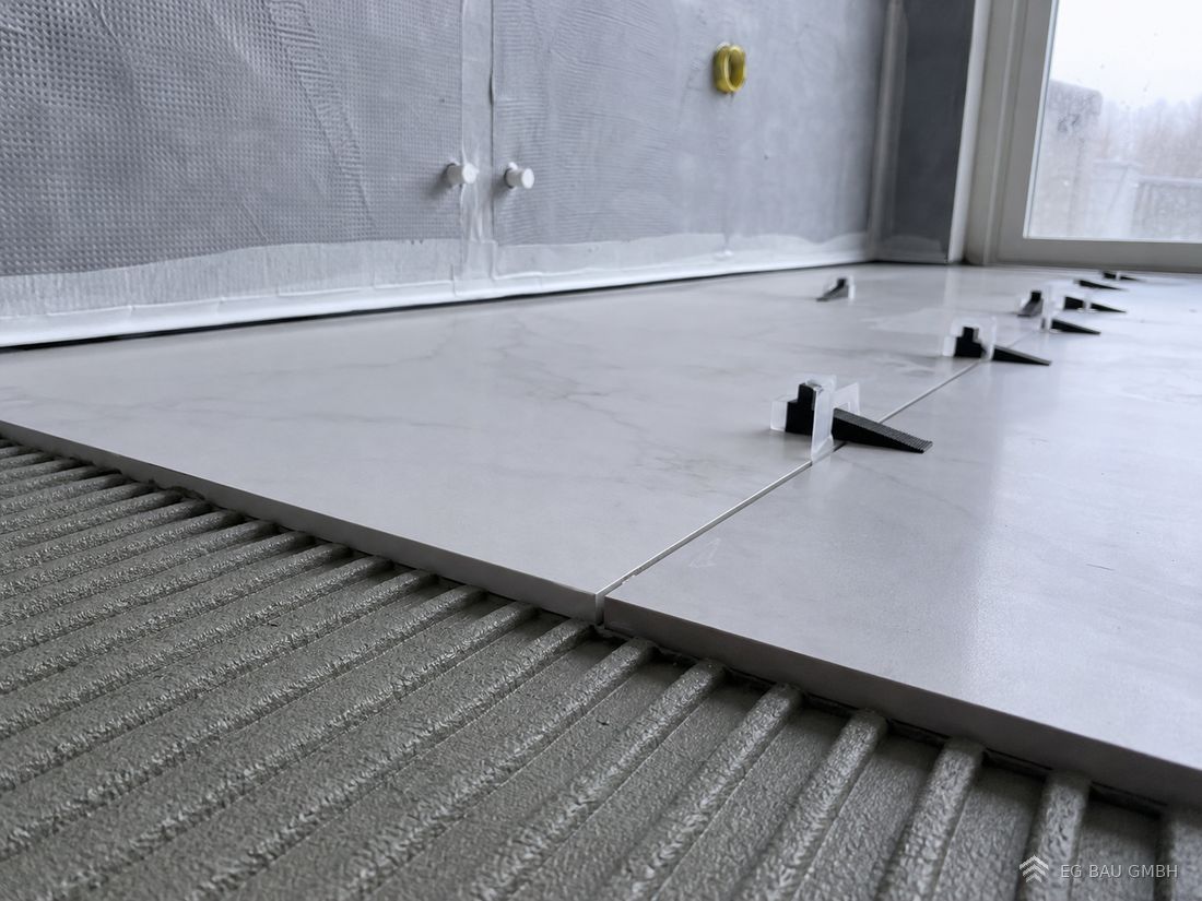 Großformatige Fliese im Dünnbettmörtel mit Nivelliersystem und Verbundabdichtung an der Wand
