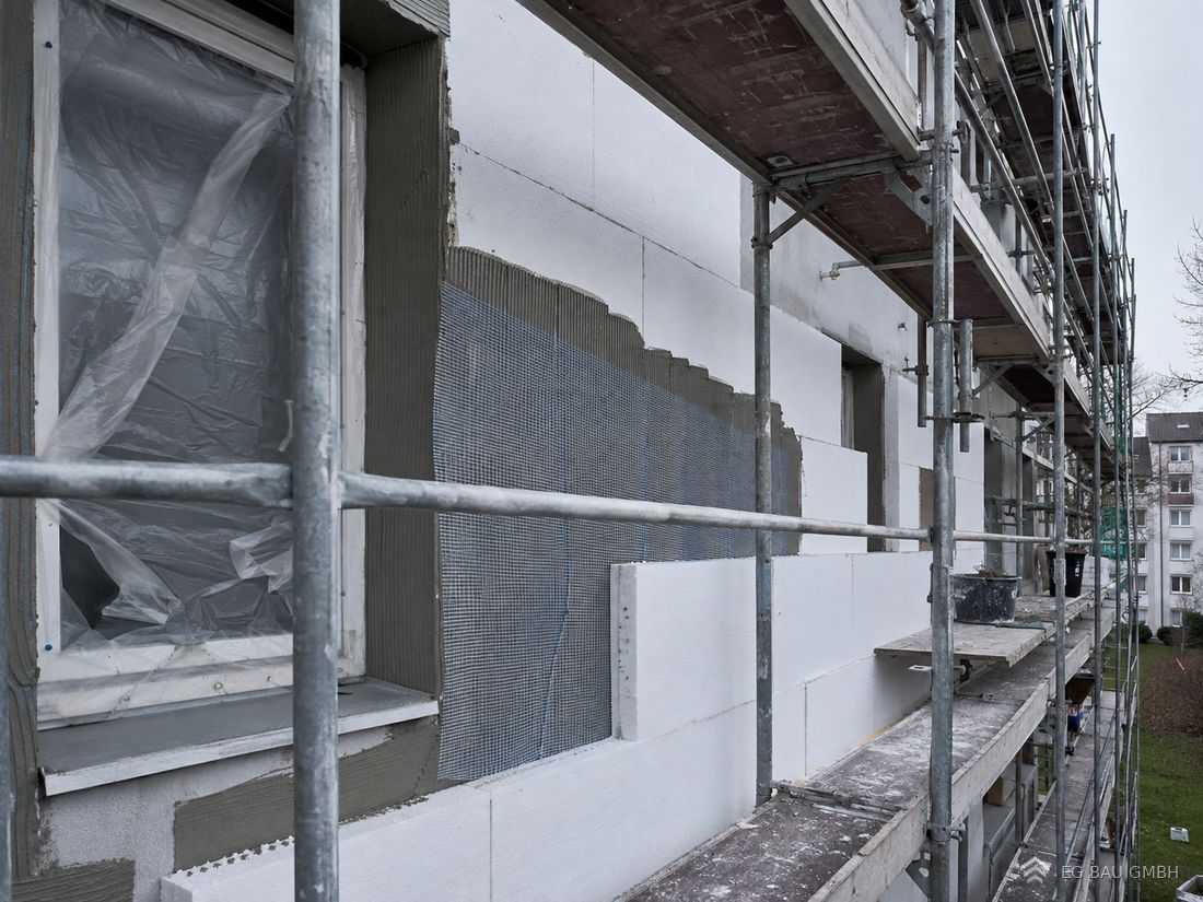 Wärmedämmverbundsystem im Aufbau: Dämmplatten und Armierungsgewebe an einer eingerüsteten Fassade